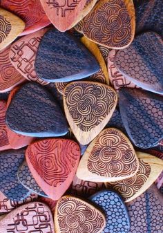 wooden guitar picks with designs on them are arranged in the shape of heart shaped shapes