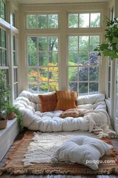 a living room filled with lots of windows next to a white couch covered in pillows