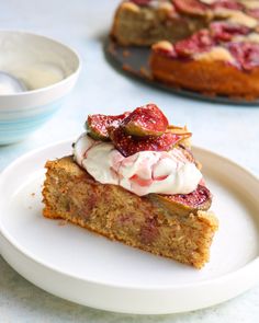 a piece of cake sitting on top of a white plate next to a bowl of yogurt