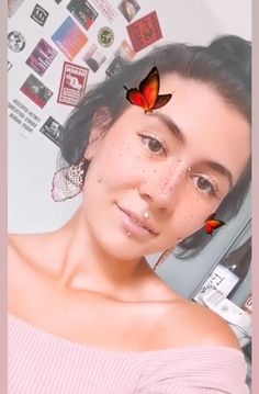 a woman with freckles on her face and two butterflies flying over her head