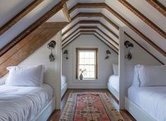 there are two beds in the attic with white linens and pillows on top of them