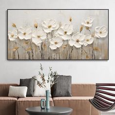 a living room with a couch, table and painting on the wall above it that has white flowers