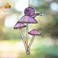 a stained glass ornament with three purple mushrooms hanging from it's side