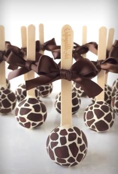 giraffe print cake pops with wooden sticks sticking out of them and tied in brown bows