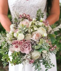 a bridal holding a bouquet of flowers and greenery in her hands, outdoors