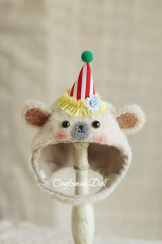 a stuffed animal wearing a hat on top of a wooden pole with a white base