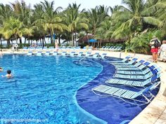 an empty swimming pool with lounge chairs and palm trees