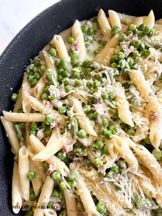 pasta with peas and parmesan cheese in a black bowl on a white table