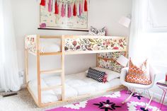 a bunk bed sitting in the corner of a room with pillows on top of it