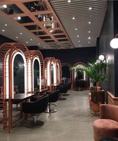 the interior of a salon with lots of chairs and mirrors on the walls, along with potted plants