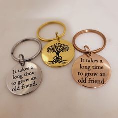 three keychains with different sayings on them, one has a tree and the other says it takes a long time to grow an old friend