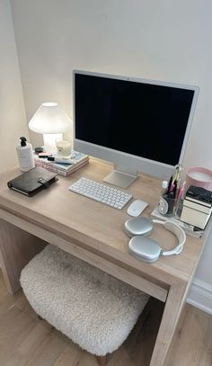 a desk with a computer monitor, keyboard and mouse on it in front of a lamp