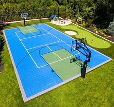 an aerial view of a basketball court with a blue surface and green grass surrounding it