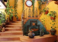 there are many potted plants on the stairs in this house with a clock above it