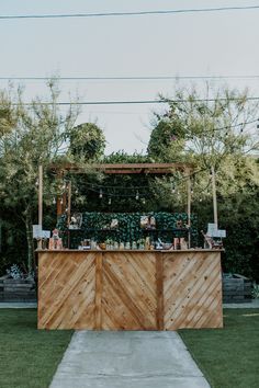 an outdoor bar is set up in the middle of a lawn with lots of greenery