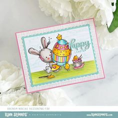 a close up of a card with flowers in the background and a bunny holding an egg