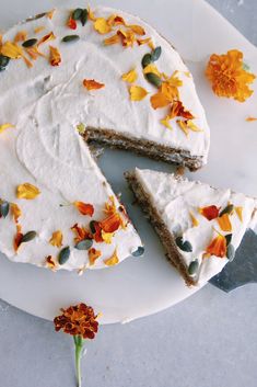 there is a cake with white frosting and flowers on the plate next to it