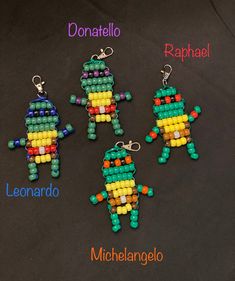 four beaded keychains with different colors and shapes on black background, including one in the shape of an alien