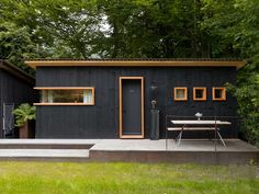 a small black house with wood trim and windows