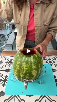 a woman cutting up a watermelon with a knife