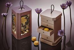 an assortment of jewelry boxes with purple flowers in the back and gold accents on top