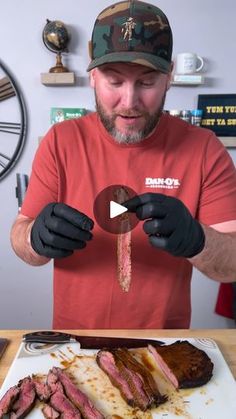 a man in a red shirt and black gloves is holding a piece of meat on a plate