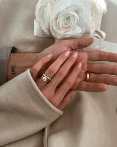 the bride and groom are holding hands with their wedding rings on top of each other