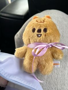 a brown teddy bear sitting on top of a person's lap with a pink ribbon around its neck