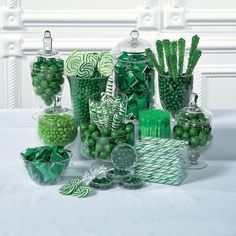 many green candies and candy in glass vases on a white table with wallpaper