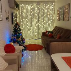 a living room filled with furniture and a christmas tree in front of a curtained window