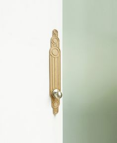 a door handle on the side of a white and green wall with an ornate design