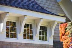 an image of windows on the side of a house with fall foliage in the background