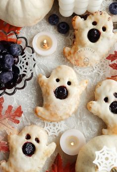 some cookies with blueberries on them are sitting on a table next to candles and pumpkins