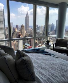 a bedroom with a view of the city from it's high rise window sill