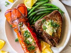 lobster, green beans and lemon wedges on a white plate