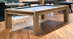 a pool table in the middle of a wooden floored room with chairs around it