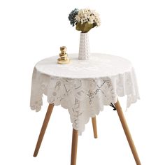 a small table with a vase on it and flowers in the center, sitting on wooden legs