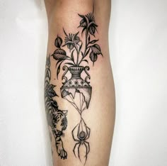 a black and white tattoo on the leg of a woman with flowers in a vase