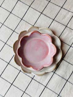 a pink and white plate sitting on top of a checkered cloth covered tablecloth