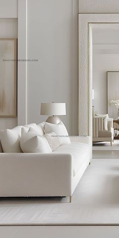 a living room with white furniture and large mirror