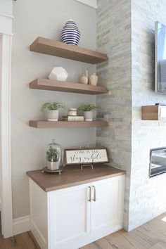 a living room with some shelves on the wall and a tv mounted above it in front of a fireplace