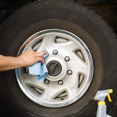 a person cleaning the rim of a truck tire with a microfibrel cloth