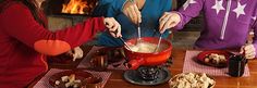 three women are preparing food in front of a fire place with bowls and utensils