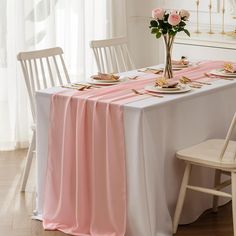 the table is set with pink flowers and gold place settings for two people to eat