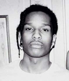 a black and white photo of a young man with dreadlocks on his head