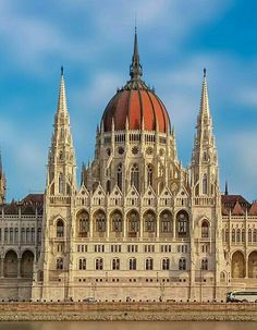 the building has many spires on it's sides and is next to a body of water