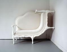 a white couch sitting on top of a gray floor next to a wall in a room