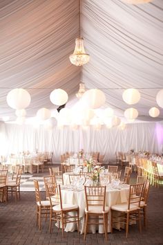 the inside of a tent with tables and chairs set up for a formal function in white linens