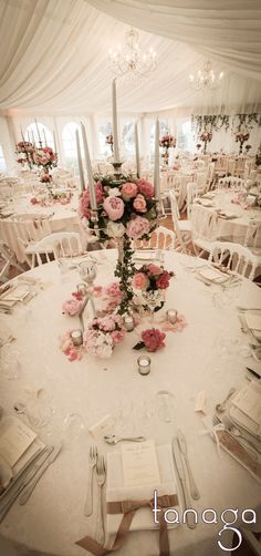 a table set up for a wedding with flowers and candles on the centerpieces