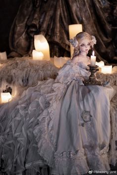 a woman sitting on top of a bed next to candles